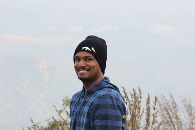 Portrait of smiling young man standing against sky