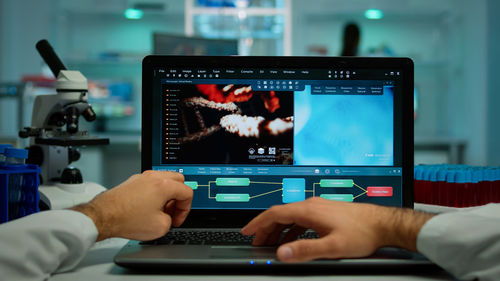 Cropped hands of scientist working on laptop in lab