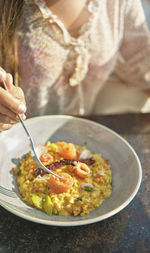 Beautiful young girl tasting a delicious risotto with smoked salmon