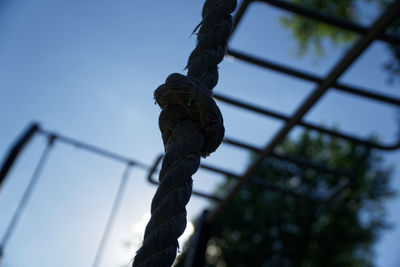 Close-up of rope tied on metal against sky