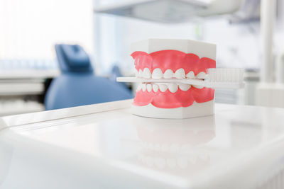 Close-up of dentures with toothbrush on table