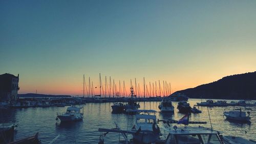 Boats moored on lake against sky during sunset