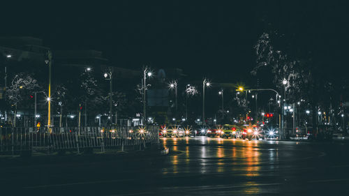 Illuminated city street against sky at night