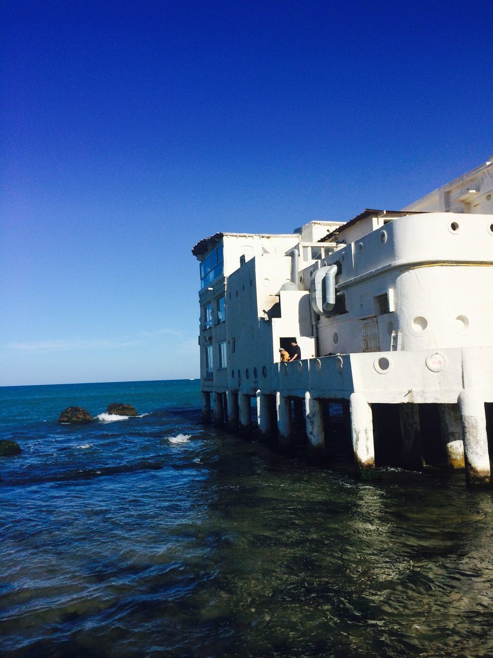 sea, built structure, architecture, water, building exterior, blue, clear sky, horizon over water, copy space, waterfront, sky, day, outdoors, nature, house, lighthouse, no people, rippled, sunlight, building