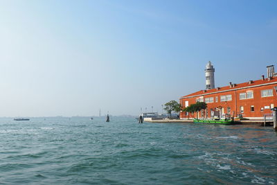 Scenic view of sea by buildings against clear sky