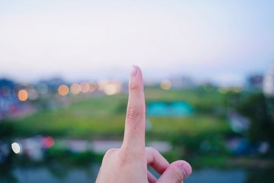 Cropped hand gesturing against sky