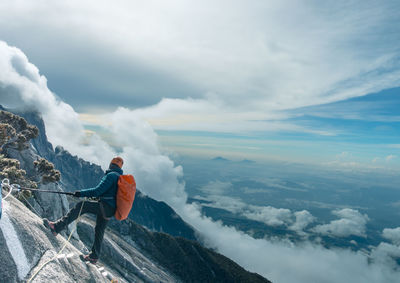 Man hiking on mountain against sky