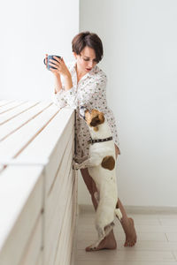 Full length of woman holding dog on mobile phone