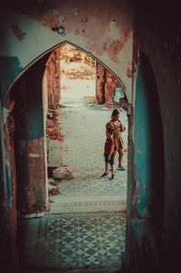 Full length of woman standing by old building