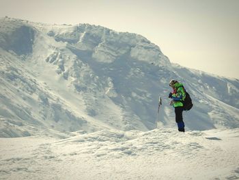 Man standing on snowcapped mountain against sky