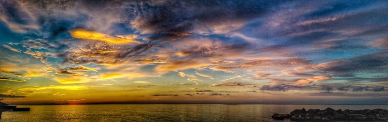 Scenic view of sea against dramatic sky during sunset