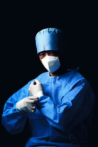 Portrait of woman wearing mask against black background