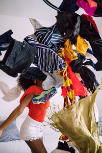 Black woman with afro hair throwing pile of clothing standing in the living room screaming