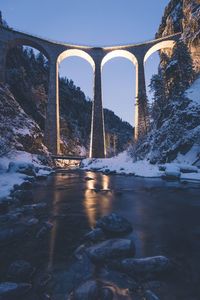 Bridge over river against sky during winter