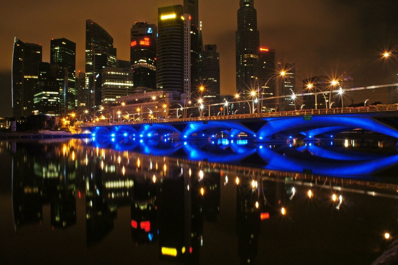 illuminated, night, building exterior, city, architecture, built structure, skyscraper, cityscape, office building, modern, city life, tall - high, urban skyline, tower, reflection, river, financial district, capital cities, water, light - natural phenomenon