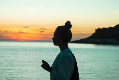 Side view of woman standing on beach against sky