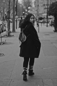 Portrait of backpack teenage girl walking on footpath in city