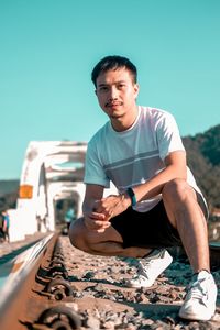 Young man sitting against clear sky