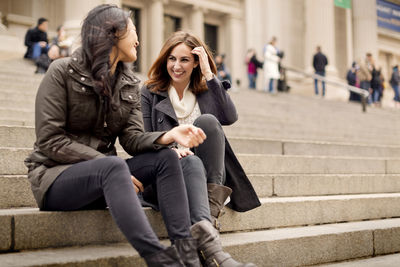 Cheerful friends talking while sitting on steps