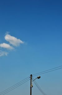 Low angle view of electricity pylon against blue sky