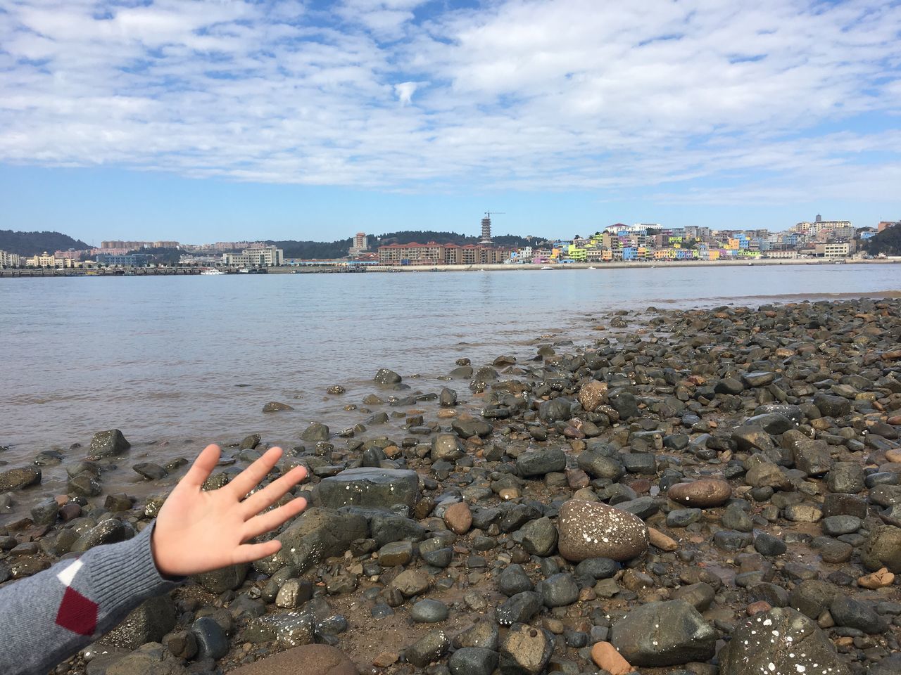 water, human body part, human hand, river, sky, one person, outdoors, leisure activity, rippled, cloud - sky, day, one woman only, nature, people, adults only, real people, women, adult, nail polish, one young woman only, only women, beauty in nature