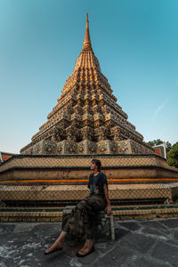 Man sitting on temple against sky