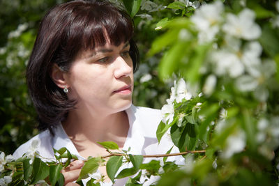 Close-up of young woman looking away against plants