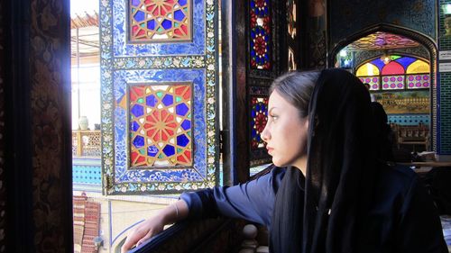 Portrait of woman looking through colorful window