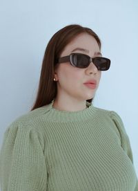 Portrait of young woman standing against white background