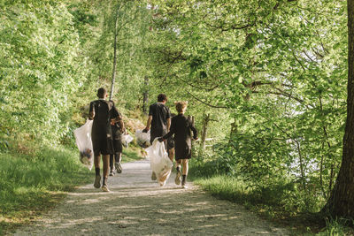 Full length rear view of boys plogging on footpath amidst green plants