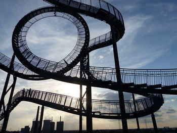 Low angle view of ferris wheel against cloudy sky