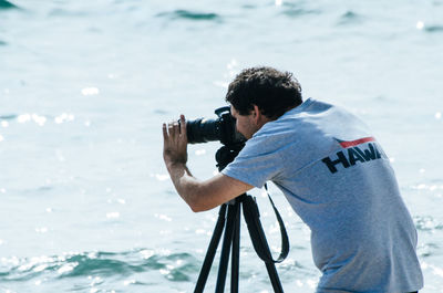 Man photographing against sea