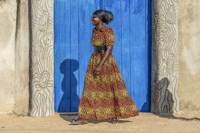 African woman with dress and headdress walks out in keta village ghana west africa