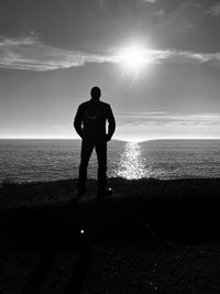 Rear view of man standing at beach taking in the sunset. 