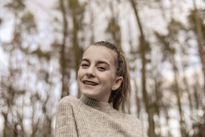 Portrait of smiling young woman against trees