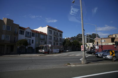 Road by buildings in city against sky