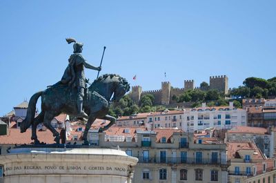 Statue in city against clear sky