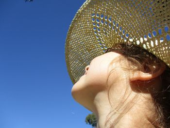 Low angle view of child against clear blue sky