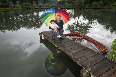 Man and the baby with umbrella on lake during rainy season