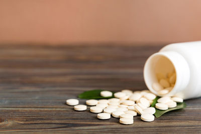 Close-up of pills spilling from bottle on table