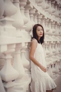 Portrait of young woman standing against white background