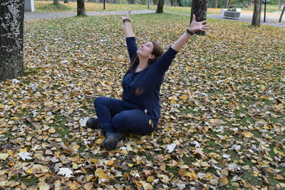 Full length of young woman sitting on road during autumn