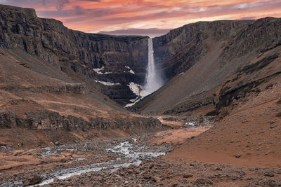 Beautiful view of hengifoss waterfall against cloudy sky during sunset