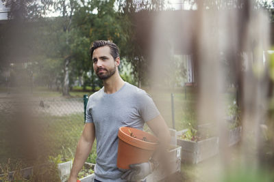 Mid adult man holding flower pot while working in urban garden