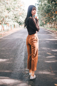 Full length of woman standing on road in city