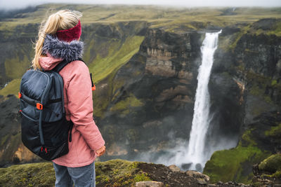 Woman with backpack enjoying haifoss waterfall of iceland highlands in thjorsardalur valley
