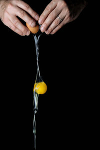 Close-up of hand holding ice cream cone against black background