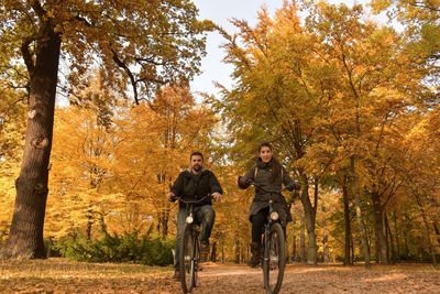 Portrait of couple riding bicycles in park during autumn 