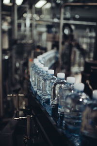 Close-up of water bottles in row on conveyor belt at factory