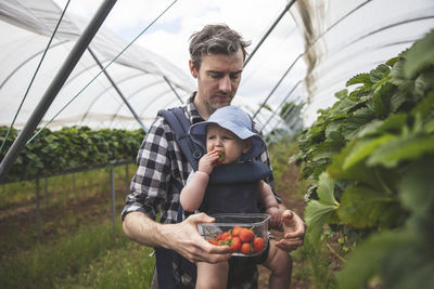 Full length of father holding daughter while standing by plants